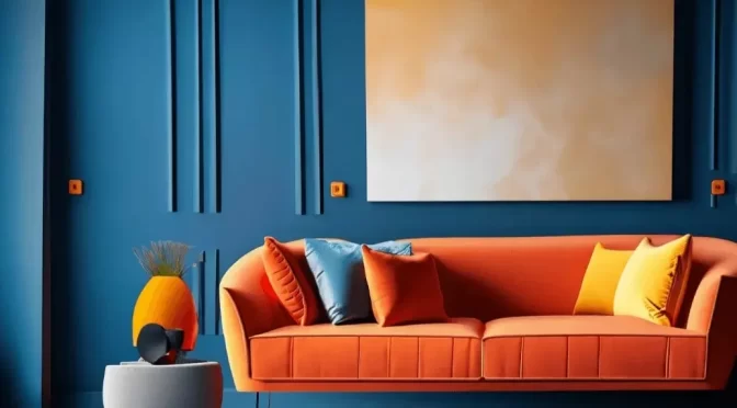 Modern living room interior with deep blue panelled wall, bright orange velvet sofa with colourful cushions, abstract wall art, and minimalist decor by Oraanj Interiors.