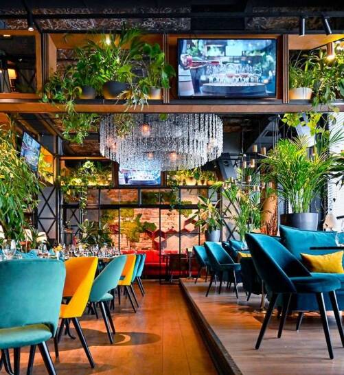 Luxury restaurant interior design with chandelier Luxury restaurant interior with crystal chandelier, indoor greenery and colourful modern seating design