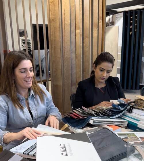 Two interior design professionals reviewing material samples and design catalogues.